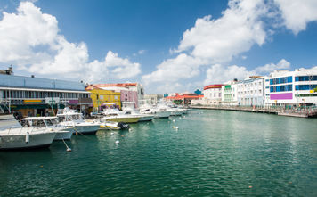 Main water canal with ships and shops in Bridgetown, capital of Barbados. Caribbean (photo via Fyletto / iStock / Getty Images Plus)