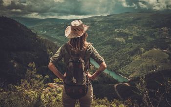 Female hiker enjoying valley landscapes from the top of a mountain.