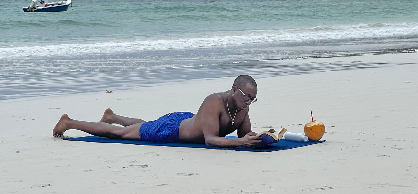 Image: An LGBTQ cruise passenger lounges on Cote D’Or beach in the Seychelles. (Photo Credit: Paul J. Heney)