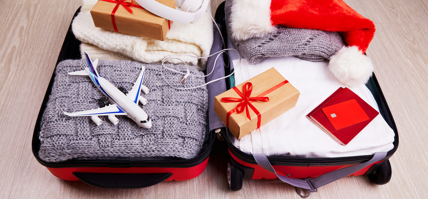 Image: Suitcase with Christmas gifts and a Santa hat. (Photo Credit: Adobe Stock/Viktoriya)