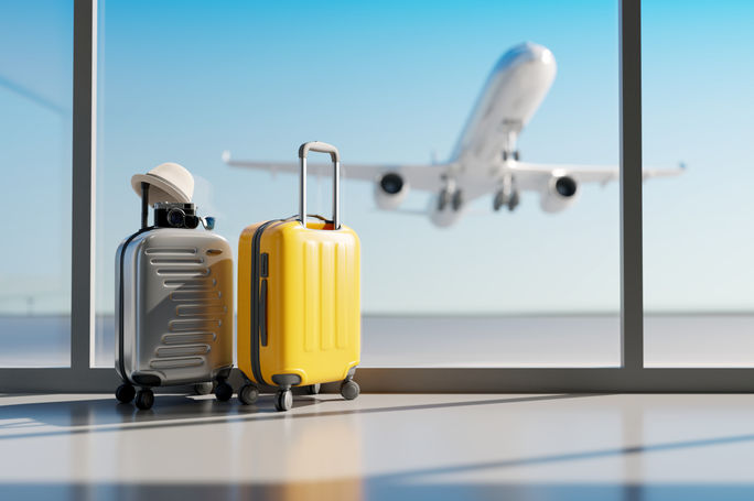 Luggage sitting at the airport with a plane taking off in the background.