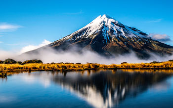 Mirroring waters of the lake alongside Mount Taranaki, New Zealand.