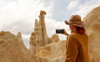 Traveler with a phone taking a picture of a mountain