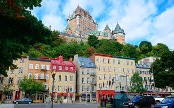 Chateau Frontenac in the day with colorful buildings on street in Quebec City (Photo via rabbit75_ist / iStock / Getty Images Plus)