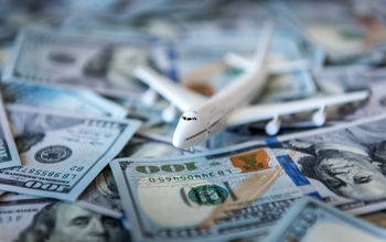 A toy airplane sitting atop a pile of US cash.