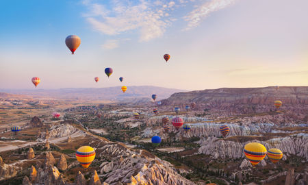 Hot air balloon flying over rock landscape at Cappadocia Turkey (photo via TPopova / iStock / Getty Images Plus)