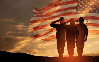 US Army soldiers saluting with an American flag in the background.